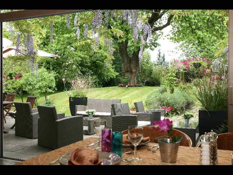 a table and chairs in a garden with a tree at Hôtel Beatus in Cambrai
