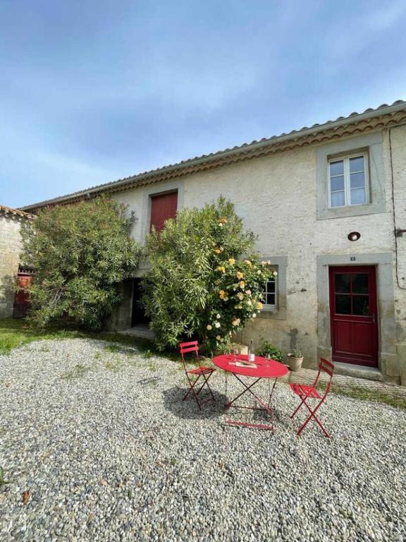 une table et des chaises rouges devant une maison dans l'établissement Le cazal, à Sainte-Eulalie