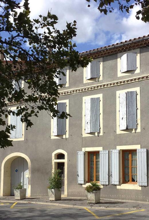 - un grand bâtiment avec volets blancs dans l'établissement Maison boutet 9, à Fanjeaux