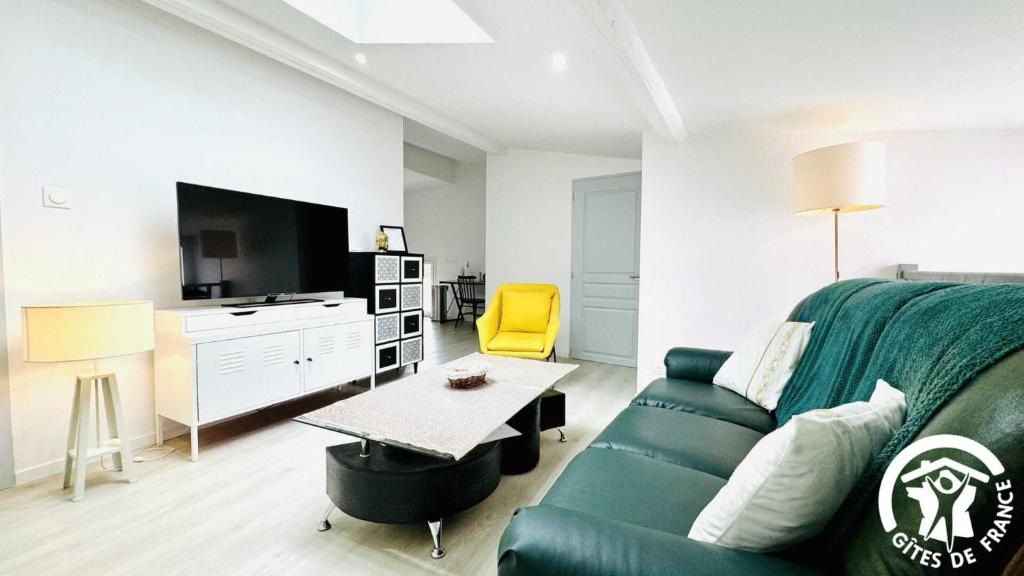 - un salon avec un canapé vert et une télévision dans l'établissement L'appartement du chateau, à Alzonne