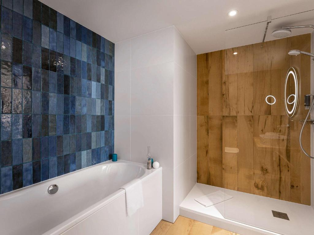 a bathroom with a tub and a glass shower at Novotel Gdańsk Marina in Gdańsk