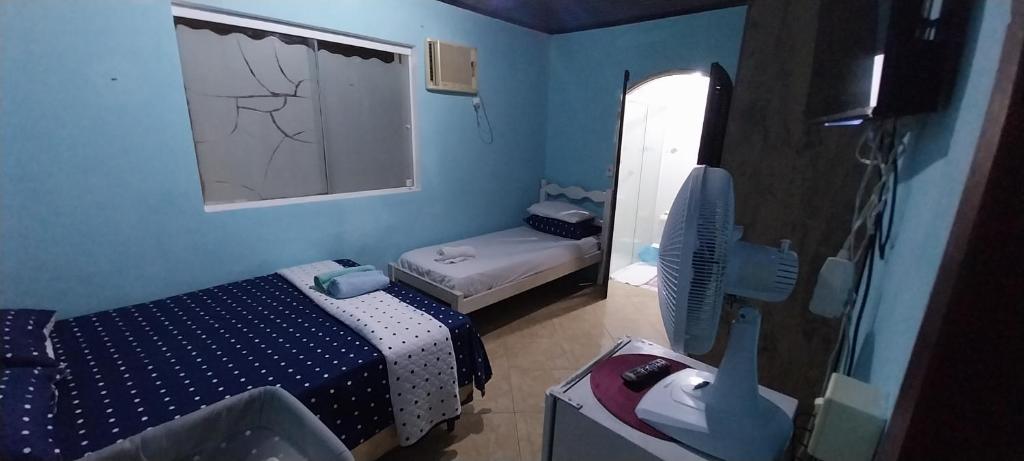 a small room with two beds and a fan at CASA DE HOSPEDAGEM PARATY 10 MINUTOS DO CENTRO COM OPÇÕES DE CAFÉ da MANHÃ in Paraty