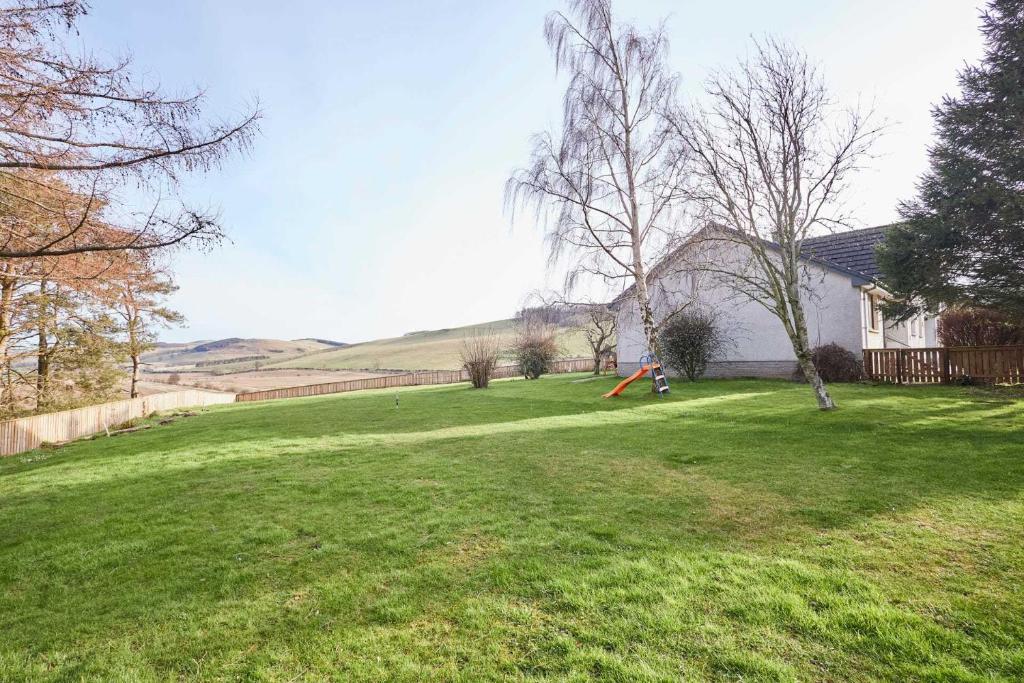 a yard with green grass and a house at Host & Stay - Audrey's Cottage in Kirk Yetholm