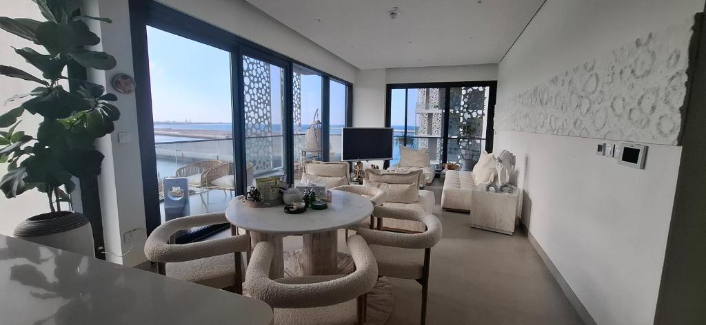 a living room with a table and chairs and windows at almoaj ,juman 2 marina view,level3 in Muscat