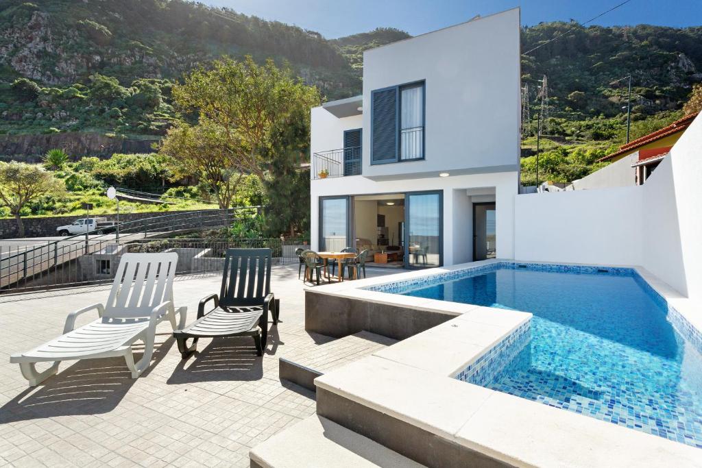 a house with a swimming pool and two chairs at Casa da Pontinha in Machico