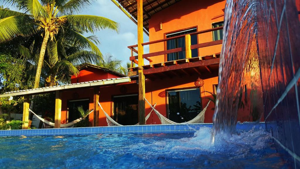 a swimming pool next to a house with a water fountain at Pousada Fasani in Ilha de Boipeba