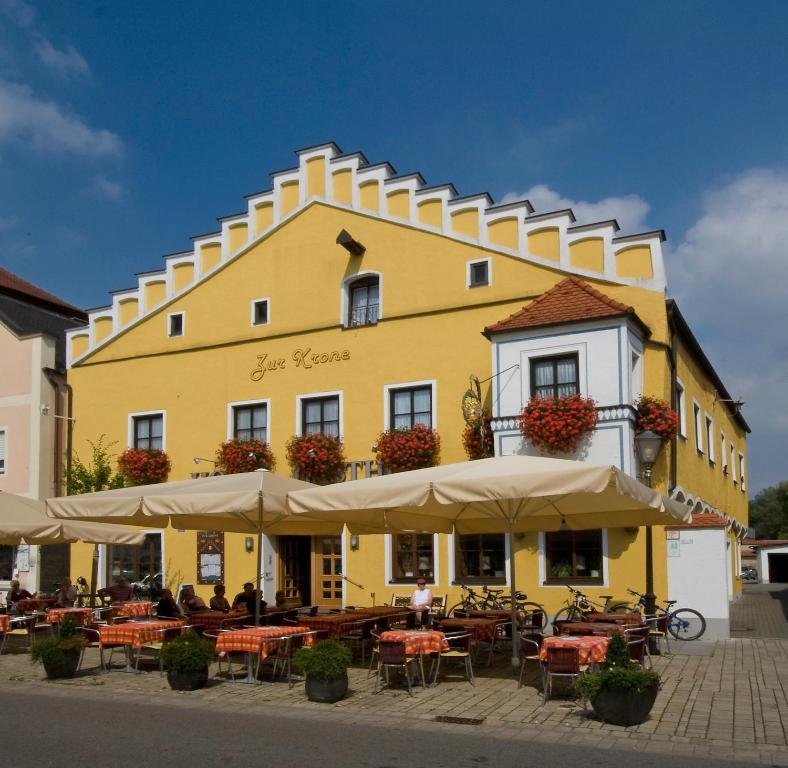 ein gelbes Gebäude mit Tischen und Sonnenschirmen davor in der Unterkunft Hotel Zur Krone in Beilngries