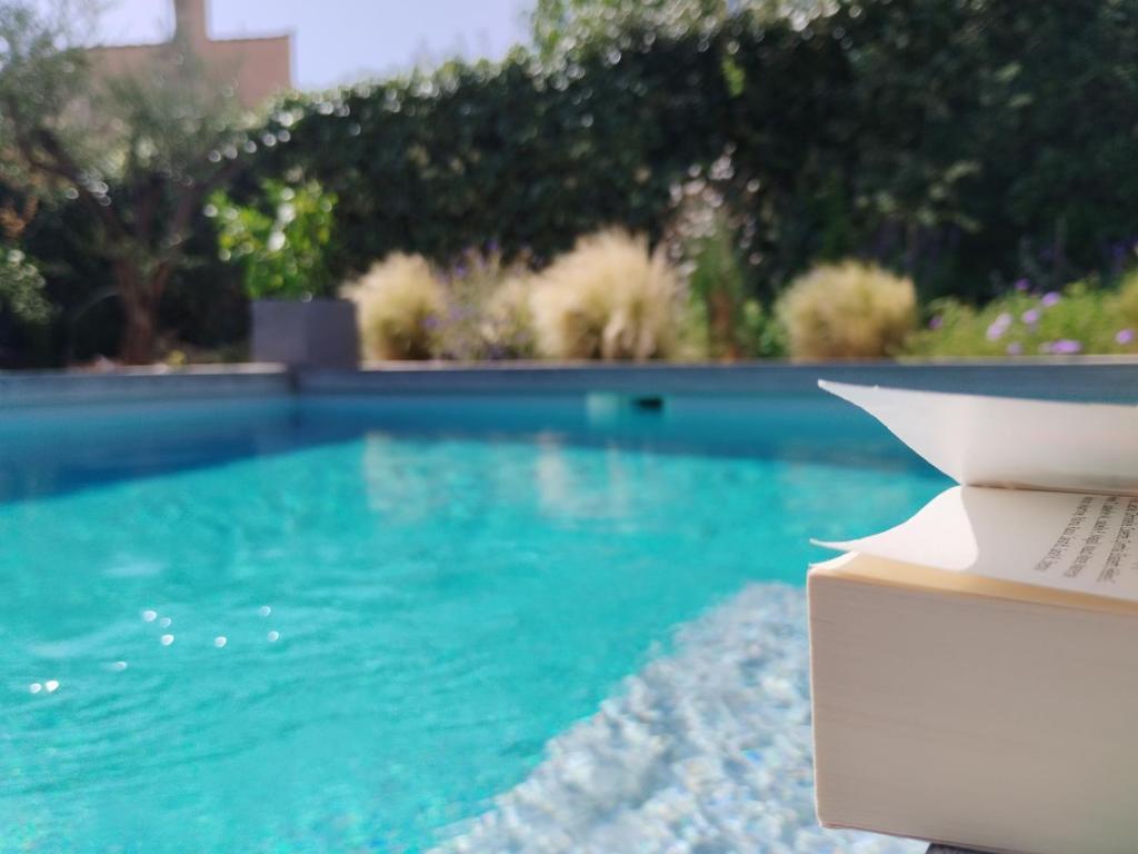 un livre assis sur une table à côté d'une piscine dans l'établissement Parenthèse à Nîmes, à Nîmes