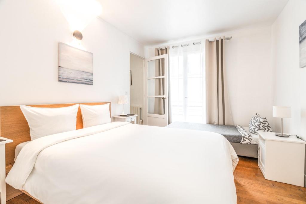 a white bedroom with a large bed and a window at Levis Charming Place in Paris
