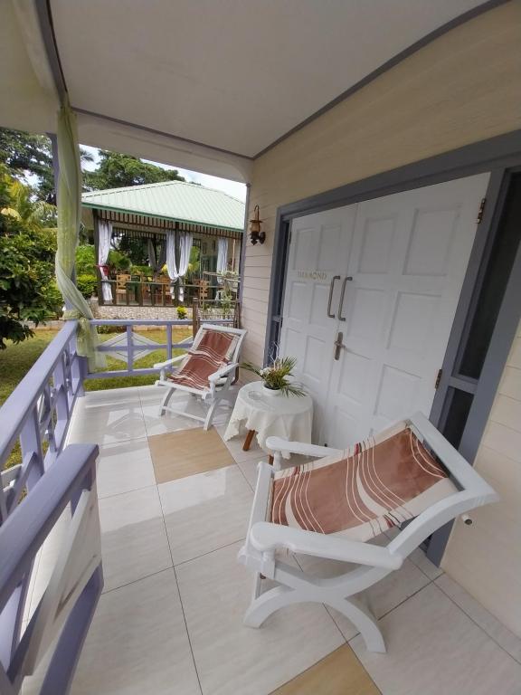 a porch with two chairs and a sliding door at Agnes Cottage in La Réunion