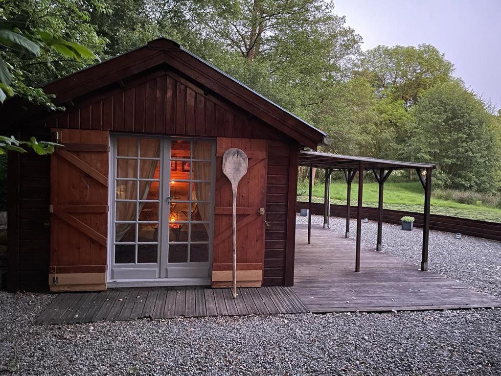 une petite cabane en bois avec une véranda et une porte dans l'établissement L'étang magique, à Plénée-Jugon