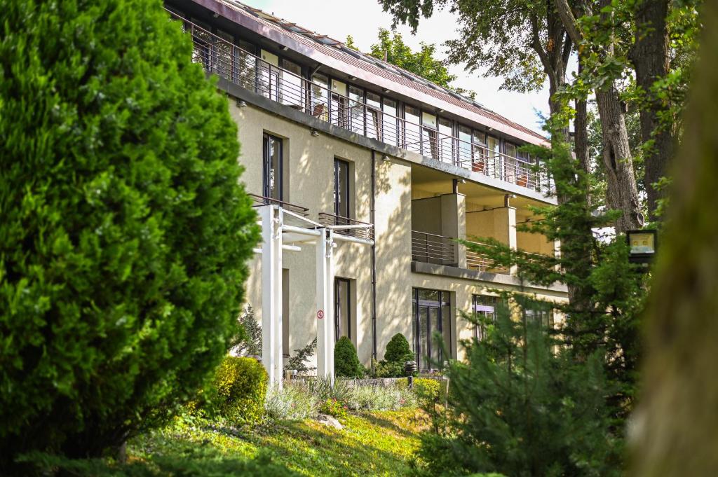 a large white house with trees in front of it at Perkuno Namai Park Hotel in Kaunas