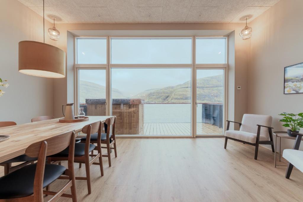 a dining room with a table and a large window at By The Sea - Boathouse with Hot Tub & Parking in Vestmanna