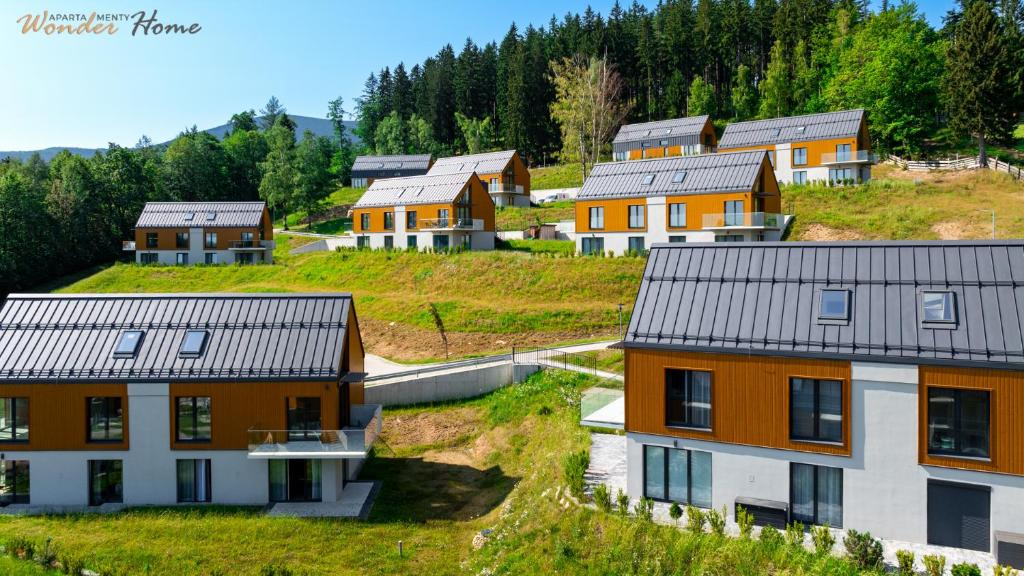 a row of houses on a hill with trees at Wonder Home - Domki Hillside tuż przy stoku narciarskim - na terenie kompleksu plac zabaw i zewnętrzna siłownia, sklep, parking in Karpacz