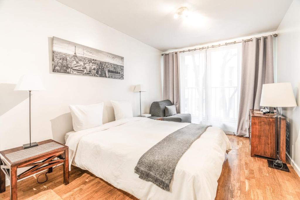 - une chambre blanche avec un lit, un bureau et une chaise dans l'établissement Champs Elysees Flat, à Paris