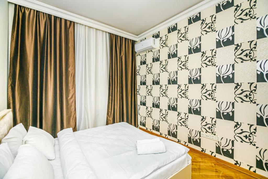 a hotel room with a white bed and a wall at Apartment BİCOCCA in Baku