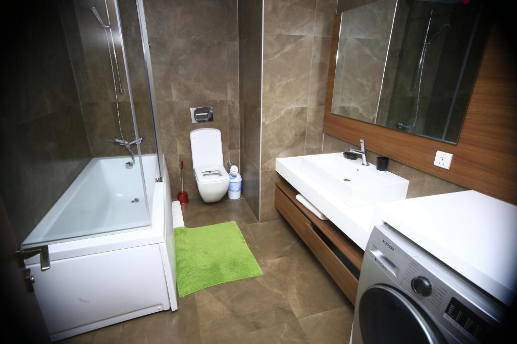a bathroom with a toilet and a sink and a washing machine at PLS Apartments Pearl-Cantonment One Bedroom in Nima