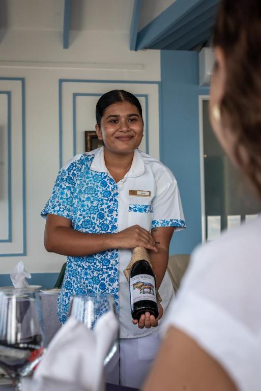 Un hombre de pie en una cocina sosteniendo una botella. en Dhigufaru Island Resort, en Atolón Baa