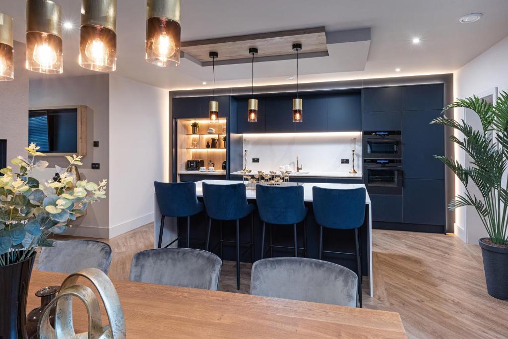 a kitchen and dining room with blue chairs and a bar at Marina West - Amble, Northumberland in Amble