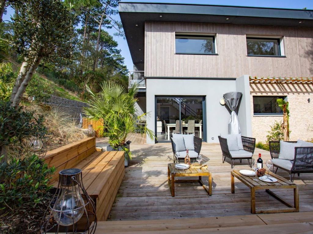une terrasse avec des chaises et des tables ainsi qu'une maison dans l'établissement Villa Spacieuse avec Spa - Calme et Proche Plage, Lac et Golfs - FR-1-791-3, à Soorts-Hossegor