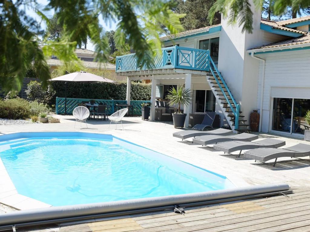 une piscine avec des chaises et une maison dans l'établissement Spacieuse villa au golf avec piscine privée, parking, et services de conciergerie - FR-1-791-23, à Seignosse