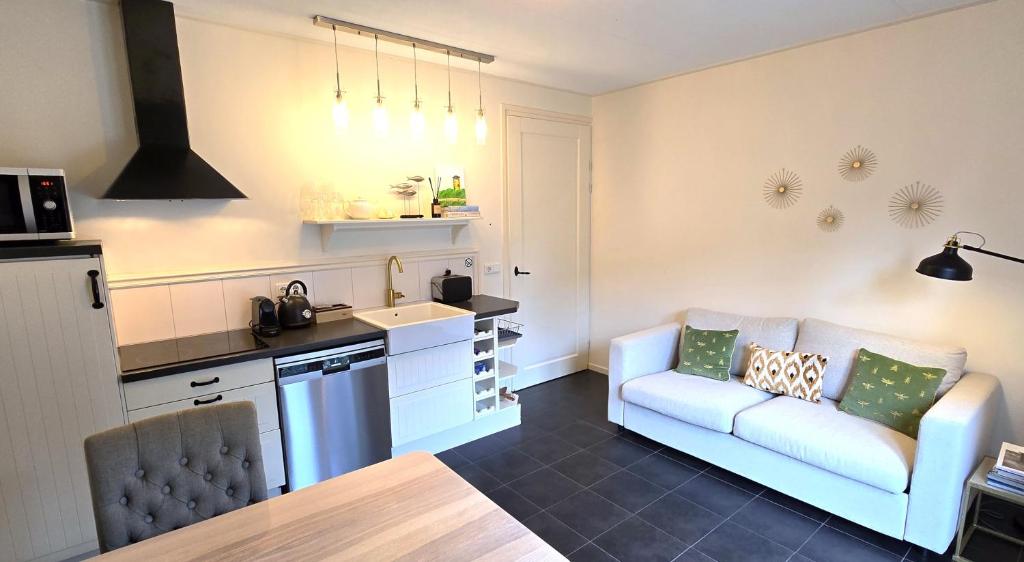 a living room with a couch and a kitchen at DJP76 mooi gelijkvloers appartement met terras in Domburg