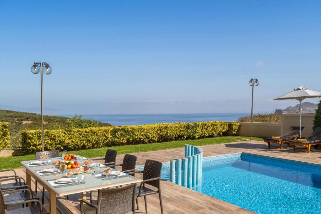 アギア・マリーナ・ネア・キドニアスにあるVilla Ariella With Sea Viewのプールサイドのパティオ(テーブル、椅子付)