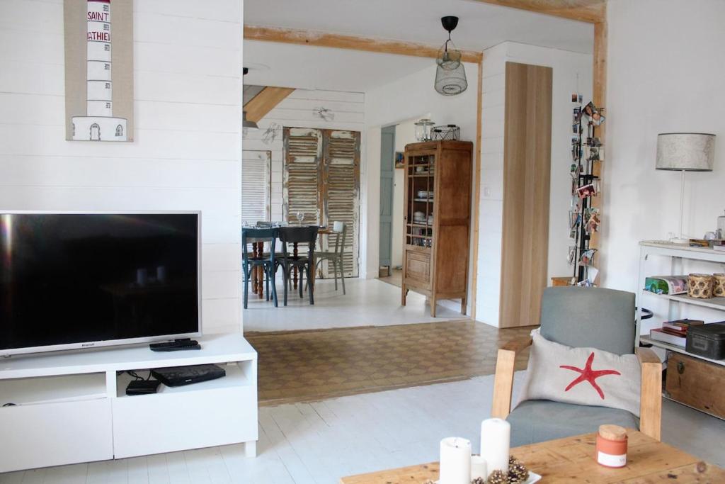 un salon avec une grande télévision et une table dans l'établissement La Maison de la Plage-100m Plage du Casino, à Saint-Quay-Portrieux