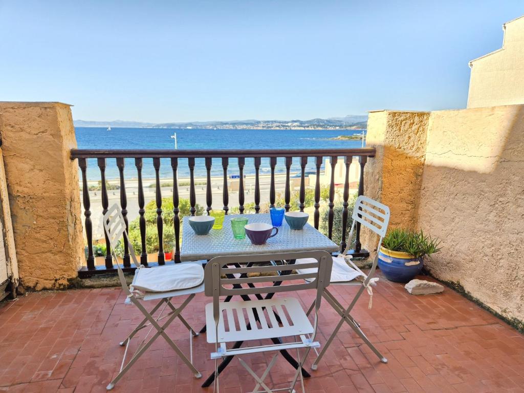 une table et des chaises sur un balcon avec l'océan dans l'établissement Pleine vue mer, à 10 m plage de sable, au Brusc, Terrasse..., à Six-Fours-les-Plages