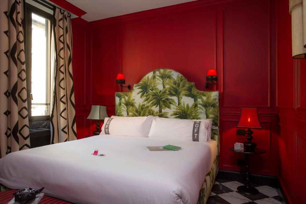 a bedroom with a large white bed with red walls at Casual Eclettico Milano by Casual Hoteles in Milan