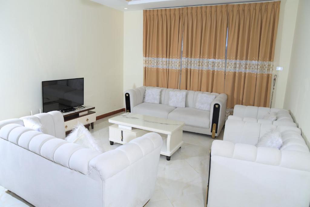 a living room with white couches and a tv at My dream apartment in Addis Ababa