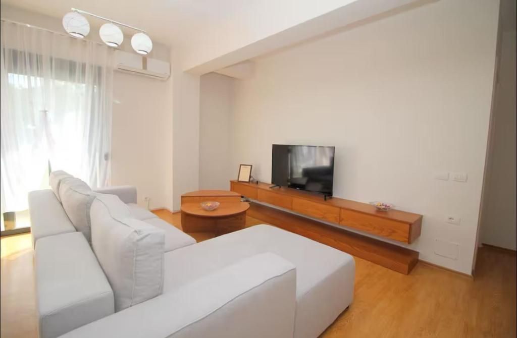 a living room with a white couch and a tv at Motra Apartment in Metogjashta