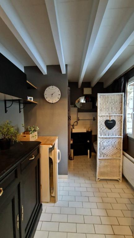 une cuisine avec une horloge sur le mur et une table dans l'établissement La Canotière - Petite maison pour 2 personnes à Vienne en Arthies, à Villers-en-Arthies