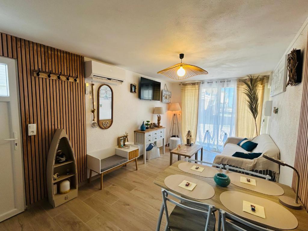 a living room with a couch a table and a fireplace at Bas de Chalet Santa Giulia in Gruissan