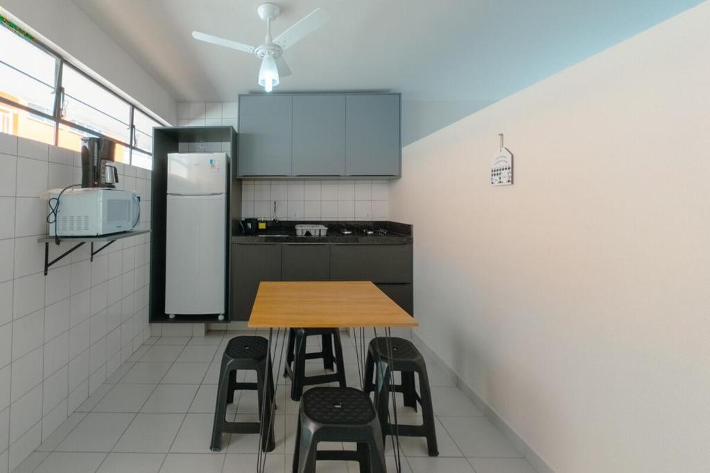a small kitchen with a wooden table and stools at Apto aconchegante na melhor região da Zona 7 in Maringá