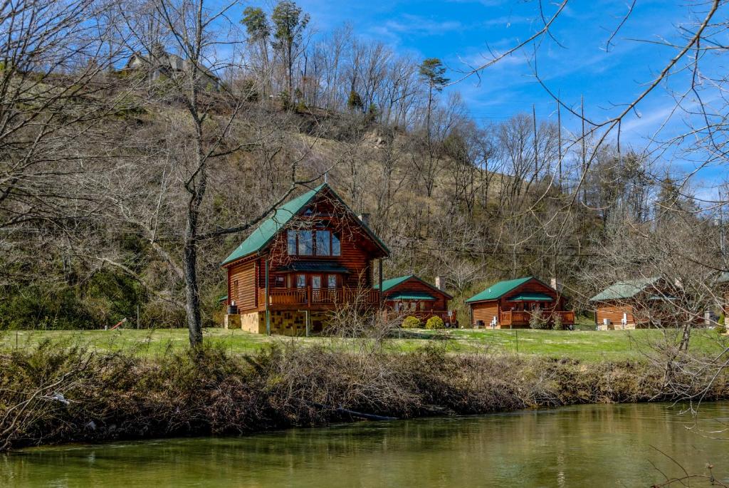 a wooden house on a hill next to a river at River Cabin in Pigeon Forge