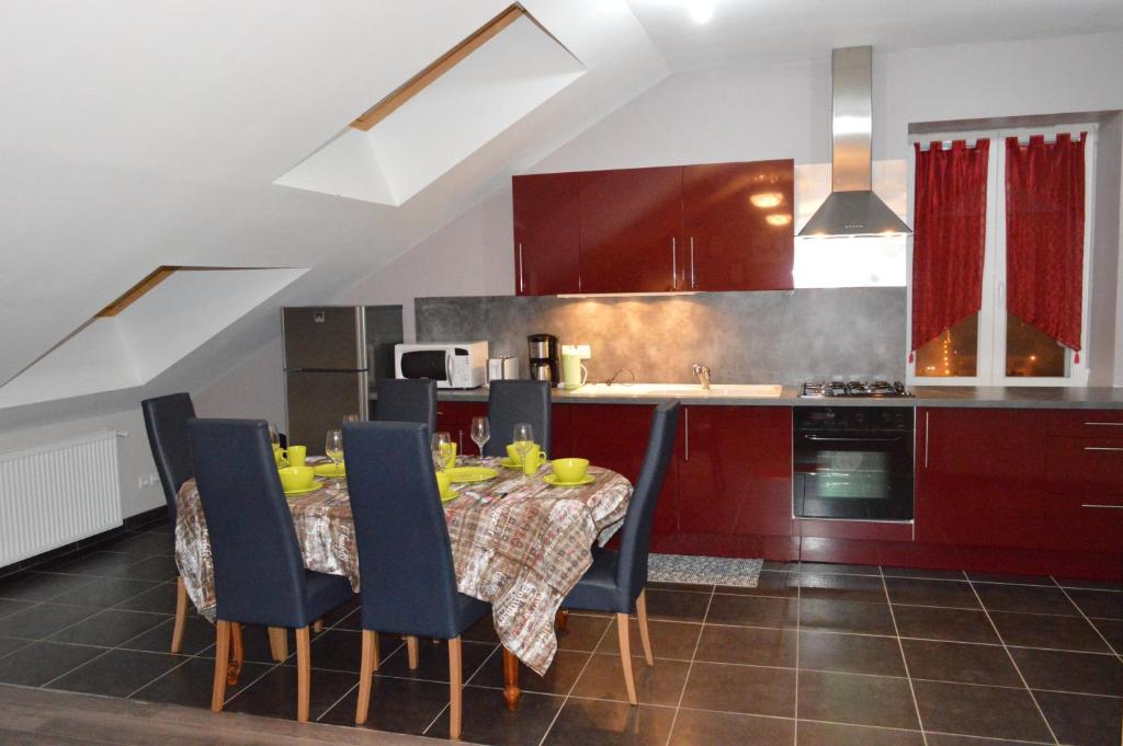 a kitchen with a table with blue chairs and a kitchen with red cabinets at Rochire Location 1 in Gérardmer