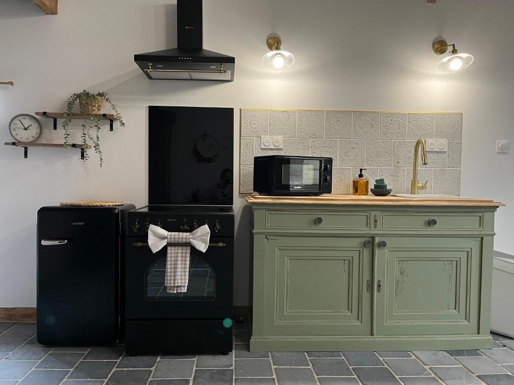 a kitchen with a black dishwasher and a microwave at La grange cottage d hôte in Landrecies