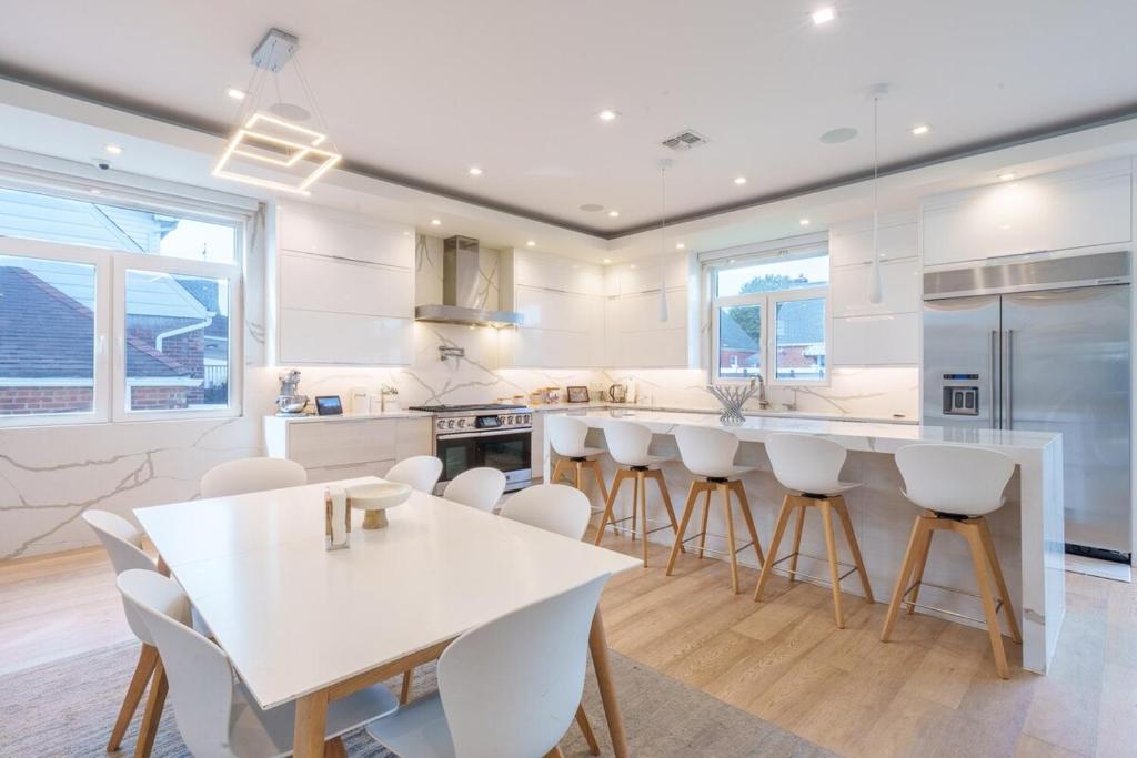 une cuisine blanche avec une table et des chaises blanches dans l'établissement Luxury 5BR Smart Home Near JFK with Gym, Theater & BBQ, à Valley Stream