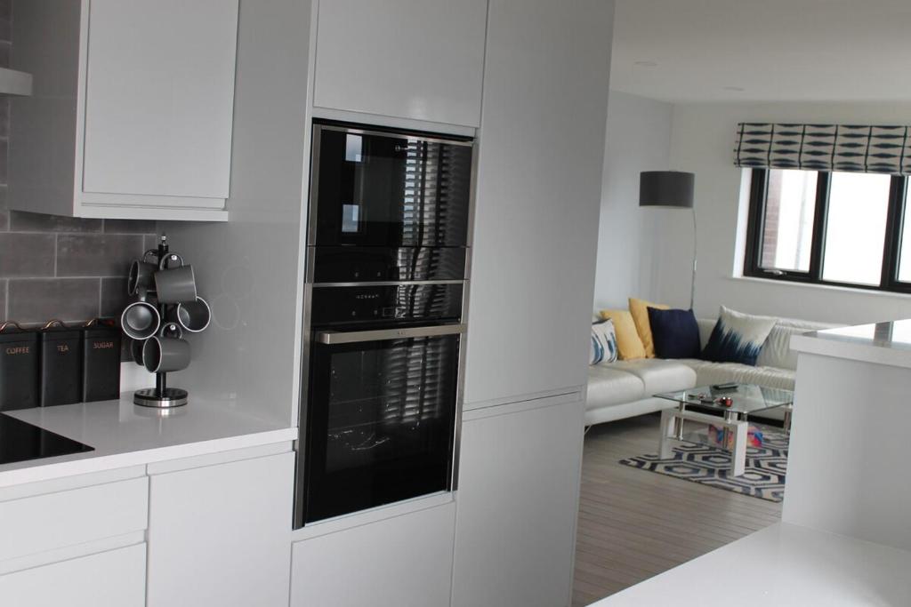 a kitchen with white cabinets and a black appliance at Beach View, Portballintrae in Portballintrae