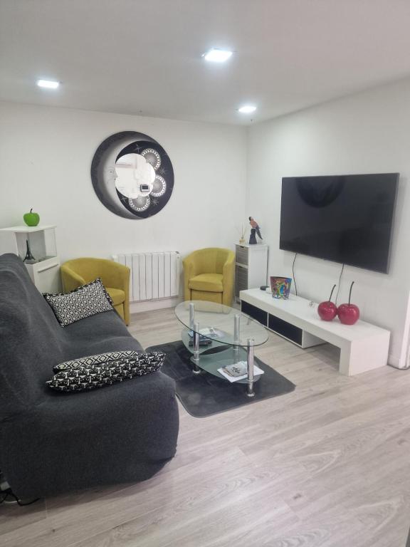 un salon avec un canapé noir et une télévision dans l'établissement Belle maison 2 chambres avec extérieur et Parking couvert, à La Ciotat