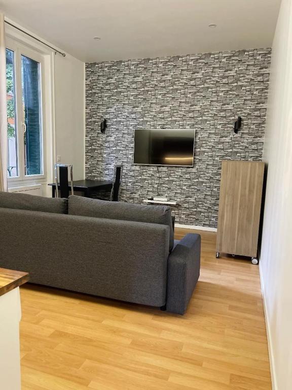 - un salon avec un canapé et une télévision sur un mur en briques dans l'établissement Beau Studio au calme !, à Villeurbanne