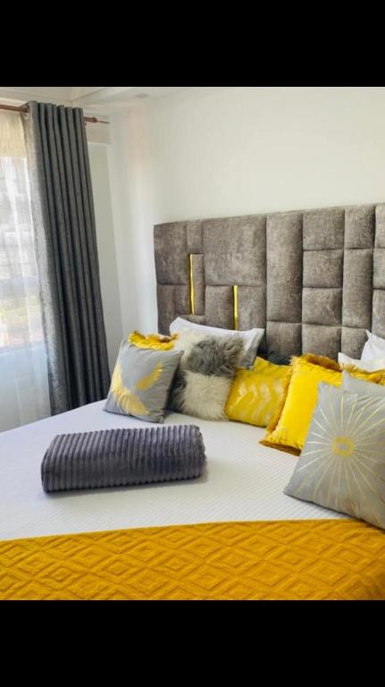 a large bed with yellow and white pillows on it at Hadassah apartment in Nairobi