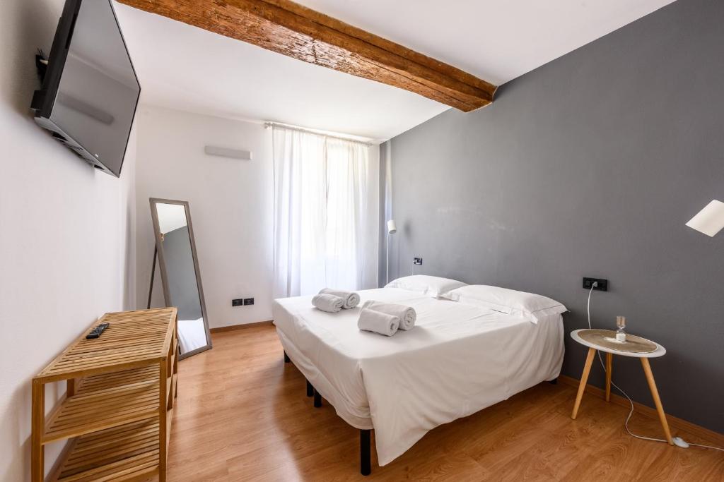 Un dormitorio con una cama blanca y un televisor de pantalla plana. en Emilia Studios 5, en Módena