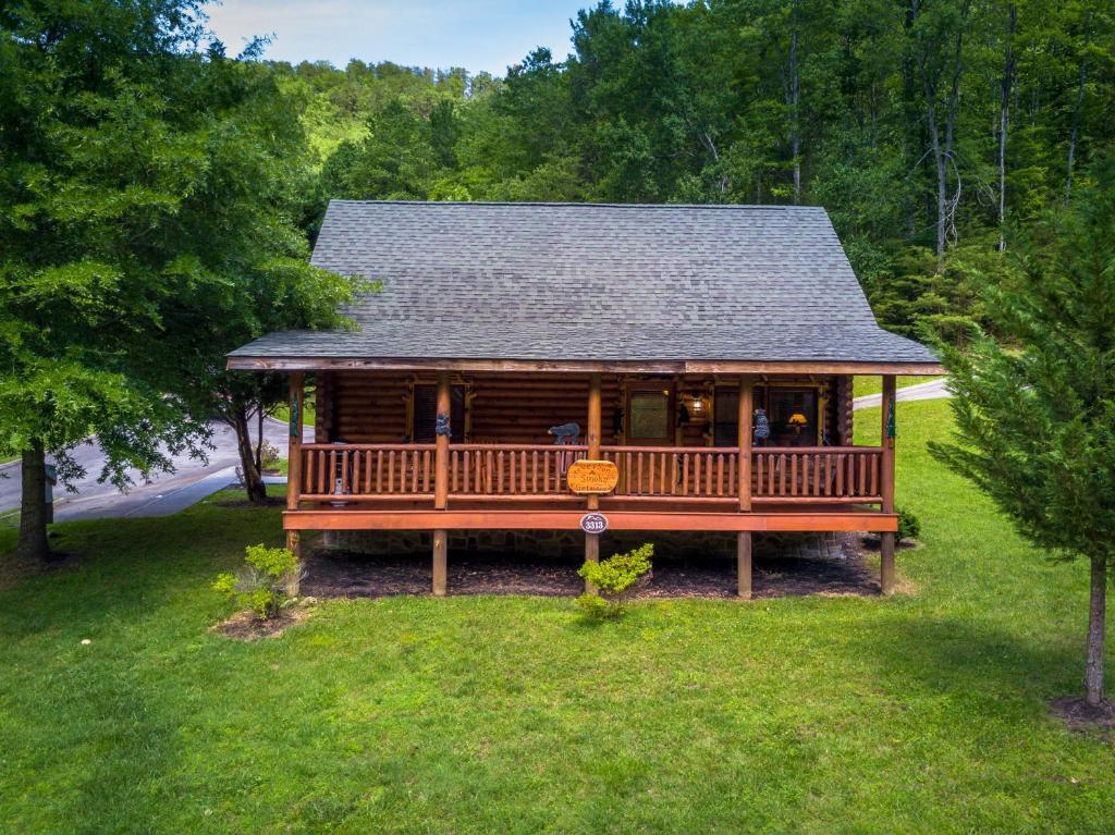 a log cabin with a large deck in the grass at A Smoky Getaway in Sevierville