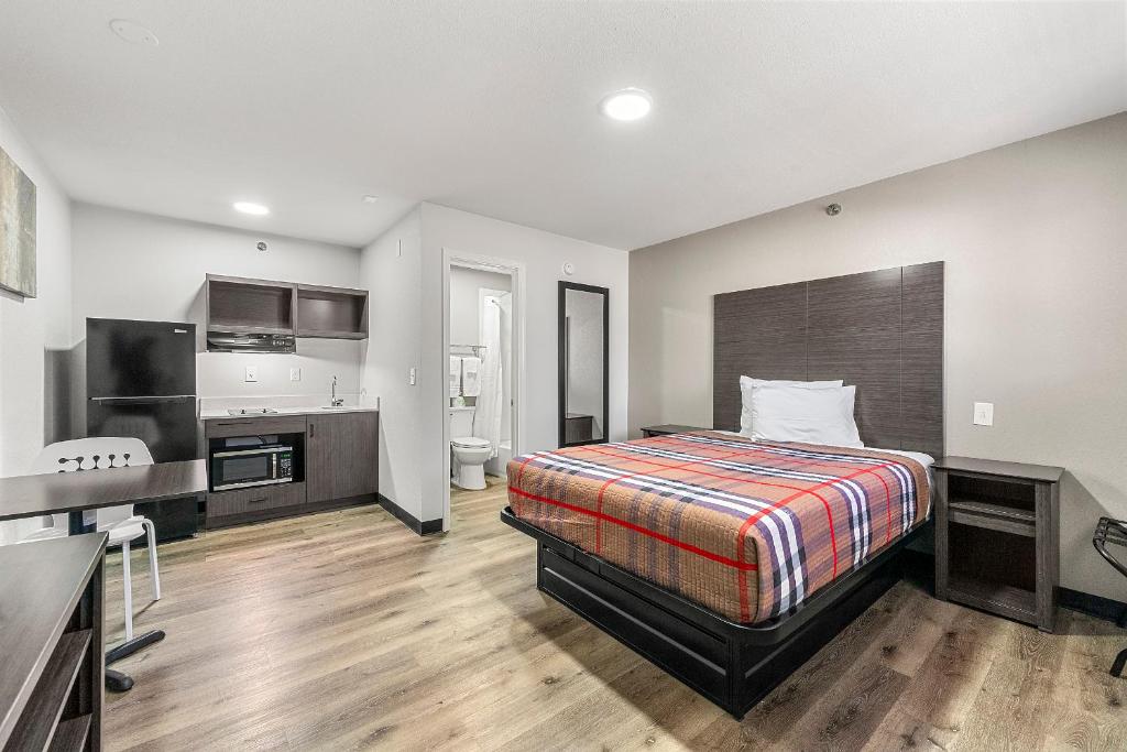 a hotel room with a bed and a kitchen at Southern Suites Forest Park in Forest Park