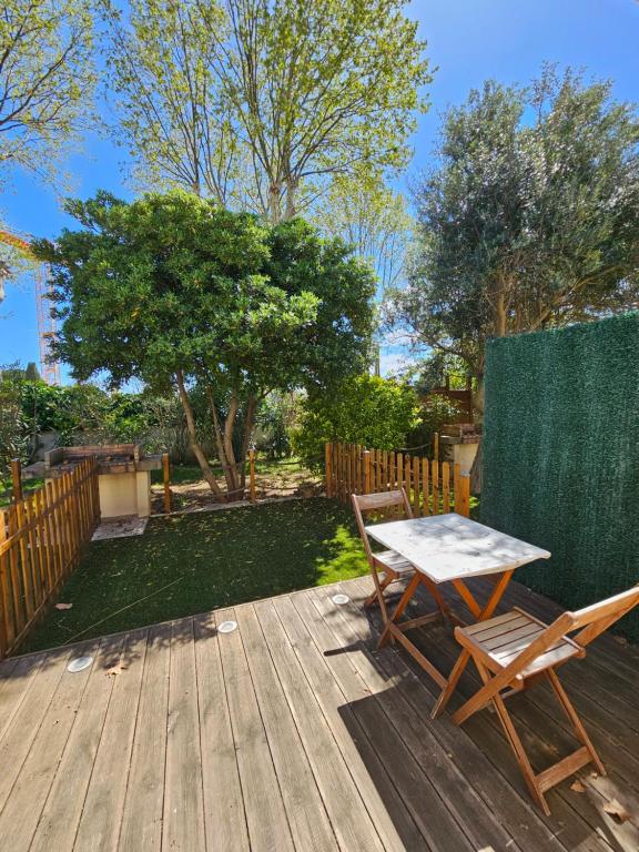 une terrasse en bois avec une table et deux chaises dans l'établissement Gîte Les Palmiers L'Escapade Des Flamants Roses, à Mireval