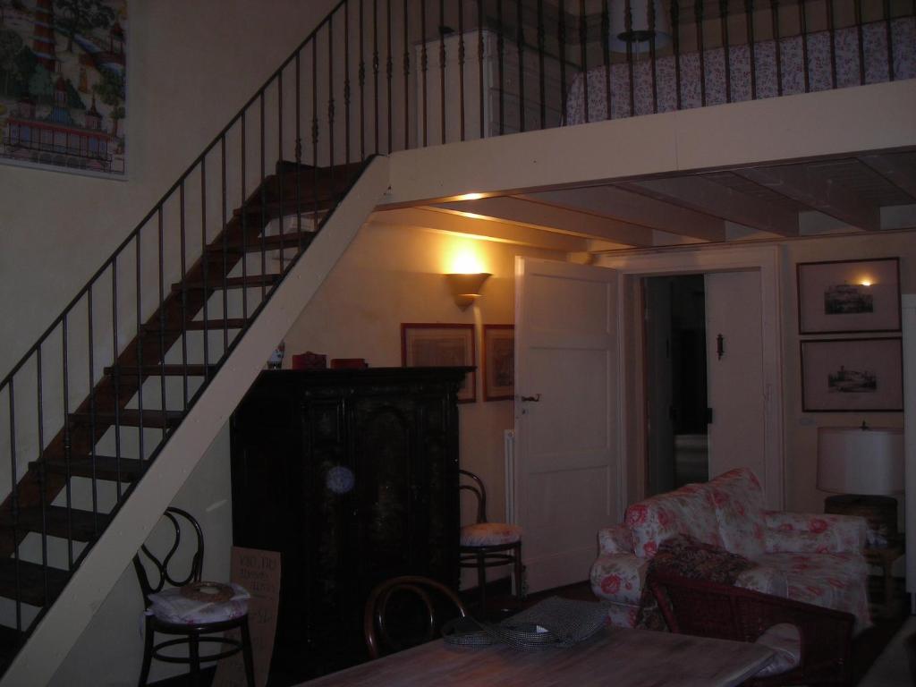 a living room with a staircase with a couch and a table at Castello di Rocca Grimalda in Rocca Grimalda