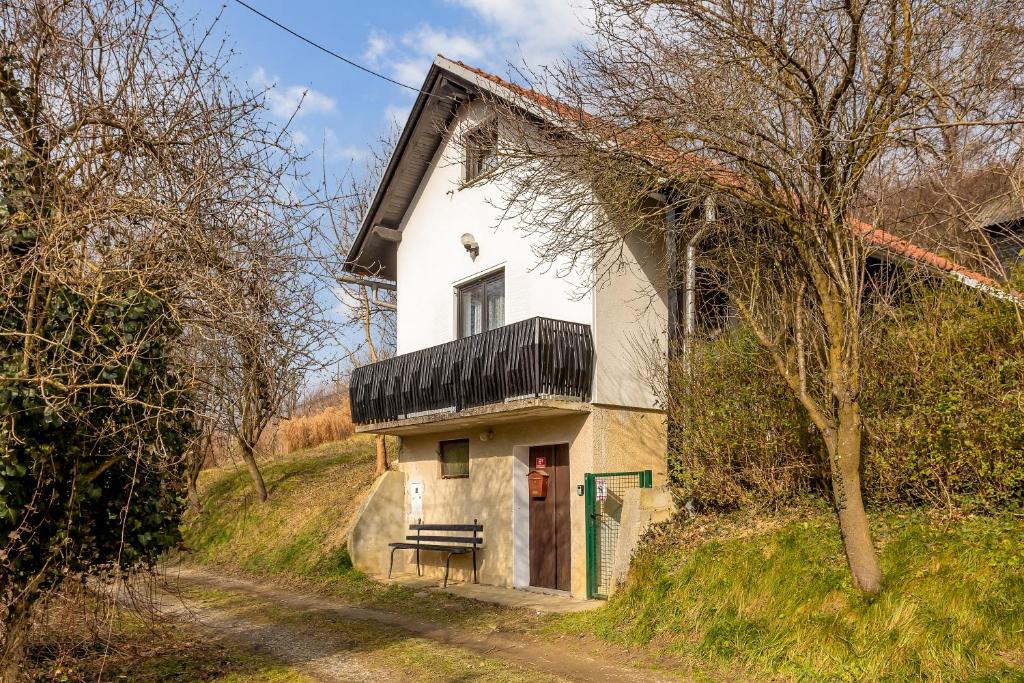une maison blanche avec un banc au bord d'une route dans l'établissement Urban Escape Cottage, à Ljutomer