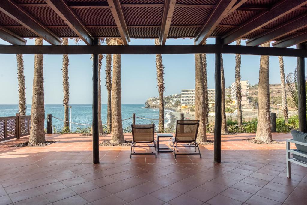 two chairs on a patio looking out at the ocean at Suite Altamar, 2 Bedroom - by Gestión Vacacional Canarias in Playa del Aguila